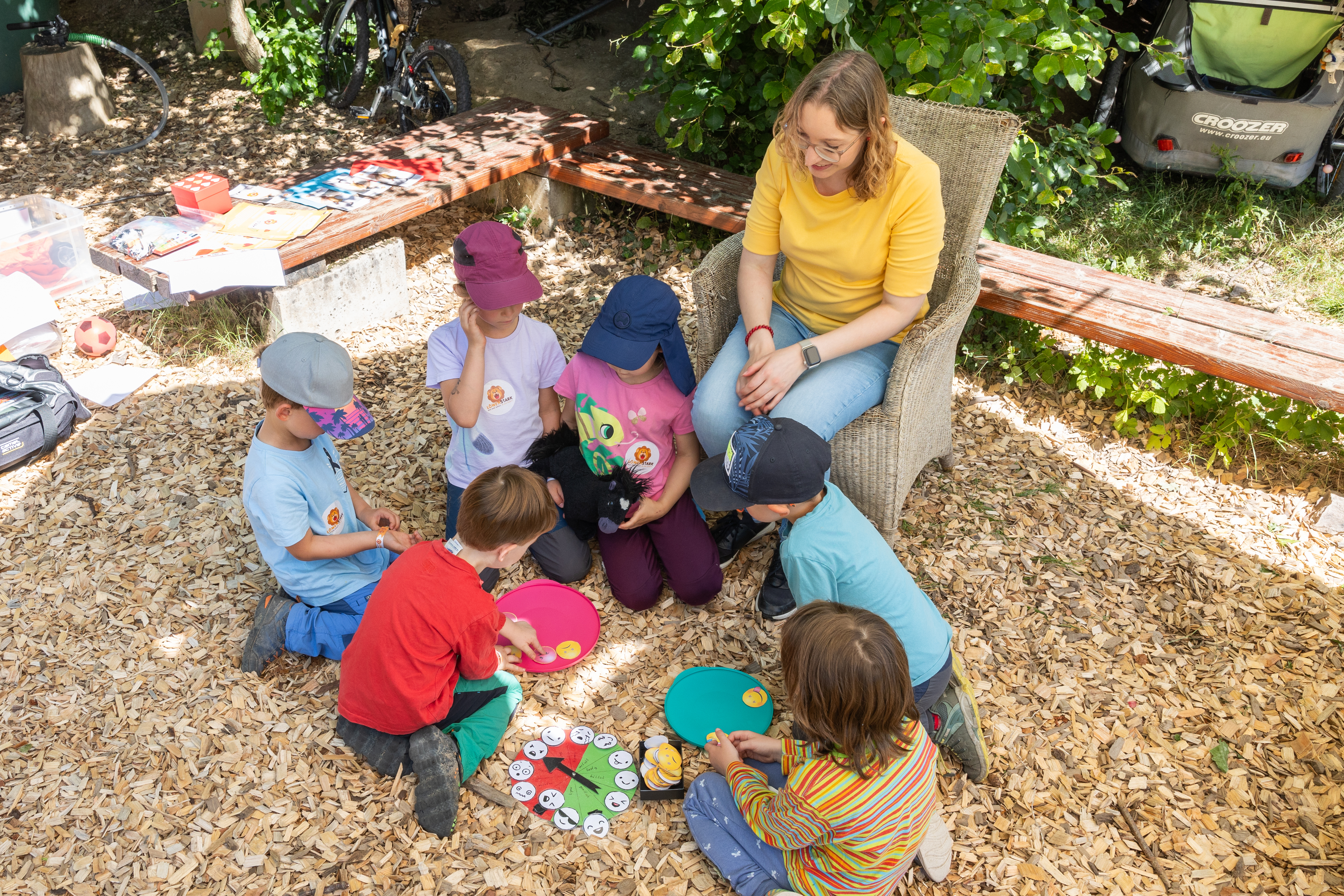 Kinder basteln einen Gefühlskompass und ordnen Smileys nach Gefühlen: rote Smileys stehen für Ärger oder schlechtes Befinden, grüne für gutes Befinden. Gefühle werden dabei gemeinsam thematisiert.