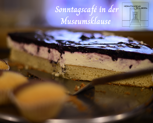 Nahaufnahme eines Schichtkuchens vom Blech. Text: „Sonntagscafé in der Museumsklause“ sowie Logo des Heimatmuseums Seulberg.