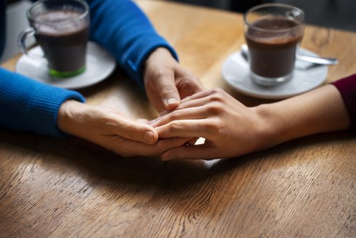 Zwei Hände die eine Hand beim Kaffe trinken halten