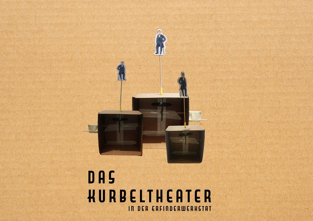 Ein Modell aus Pappe und Papier zeigt drei Miniaturbühnen mit je einer Figur in Anzug. Die Figuren sind auf kleinen Podesten platziert, die an dünnen Stangen befestigt sind. Im Hintergrund ist ein braunes, kartonartiges Material zu sehen. Unter dem Modell steht in großen, schwarzen Buchstaben ‚DAS KURBELTHEATER‘ und darunter in kleinerer Schrift ‚IN DER ERFINDERWERKSTATT‘