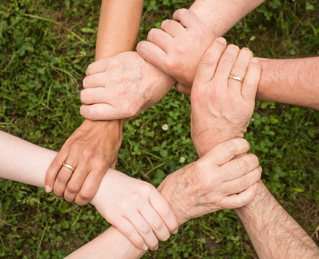 Hände von älteren und jungen Menschen, die sich im Kreis anfassen
