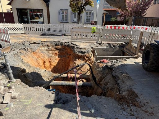 Auf dem Bild ist die vorhandene Baugrube bedingt durch die Reparaturarbeiten zu sehen, ein tiefes Loch mit freigelegten Rohrleitungen.