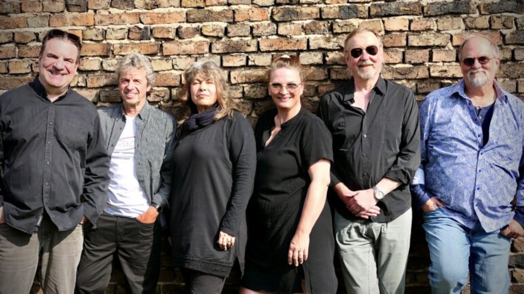  Alternativtext für Barrierefreiheit: Auf dem Bild sind die sechs Musiker der Funkkapelle Rodheim vor einer Backsteinmauer stehend zu sehen.