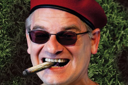 Auf dem Bild ist Kabarettist Ausbilder Schmidt mit Zigarre im Mund und Barret auf dem Kopf zu sehen.