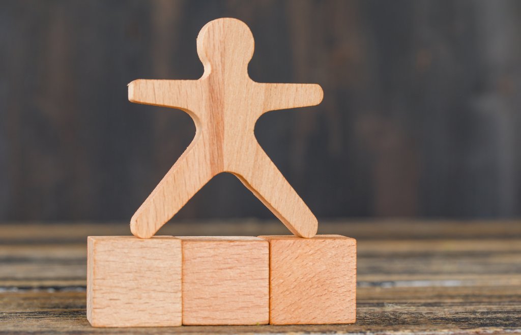Eine Holzfigur steht auf Holzklötzchen.