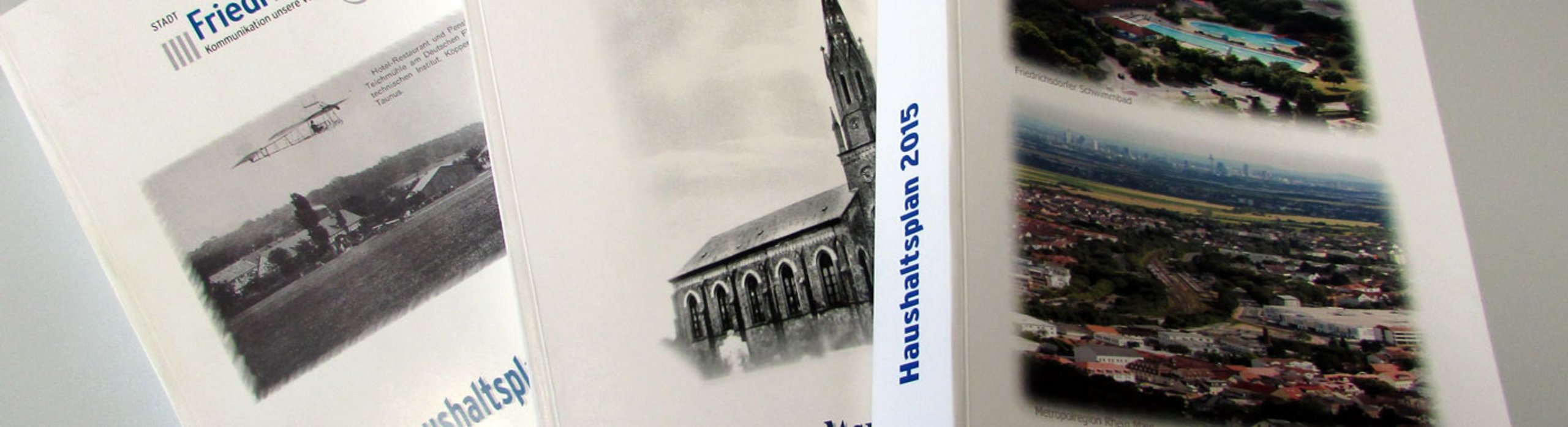 Auf dem Bild sind drei in Papierform gebundene Haushaltspläne zu sehen