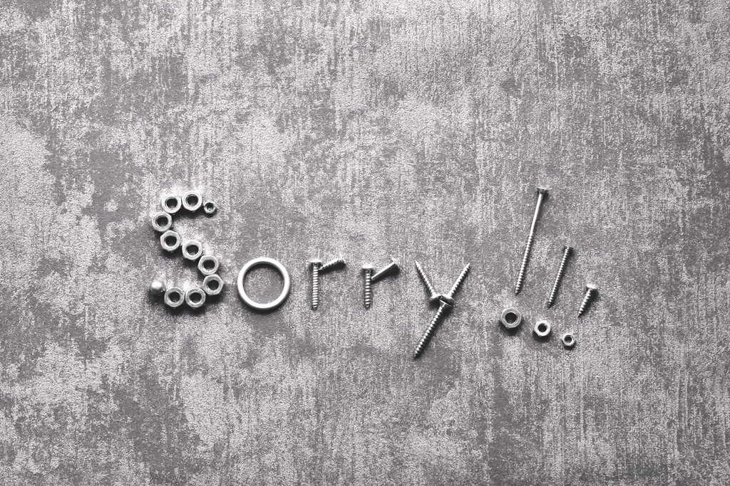 Das Wort "Sorry" aus Schrauben auf einem Beton Hintergrund