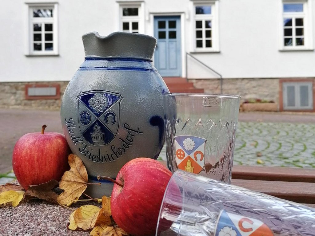 Auf der Darstellung ist ein Bembel mit zwei gerippten Gläsern jeweils mit dem Stadtwappen zu sehen. 