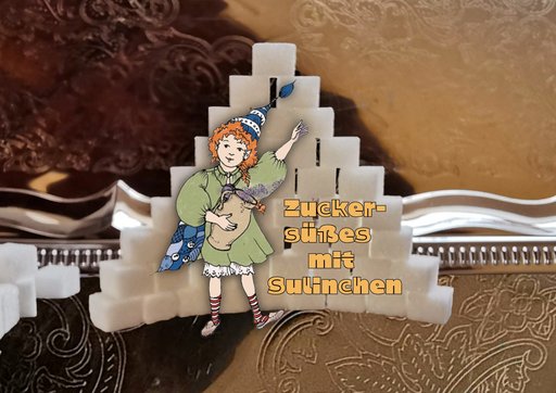 Eine kreativ gestaltete Collage, bei der eine gezeichnete Figur mit roten Haaren und einer blauen Zipfelmütze vor einer Burg aus Zuckerwürfeln steht. Die Figur trägt ein grünes Kleid, eine blau-weiß karierte Tasche und rote-weiß gestreifte Strümpfe. Im Hintergrund ist eine gold-braune, gemusterte Oberfläche zu sehen. Unter der Figur steht in orangefarbenen Buchstaben der Text: "Zuckersüßes mit Sulinchen".