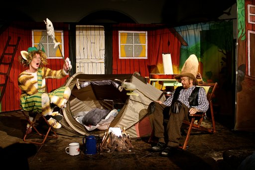 Auf dem Bild sind zwei Schauspieler in den Kostümen von Pettersonn und Kater Findus vor Bühnenkulisse zu sehen.