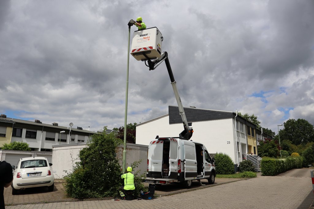 Zeigt eine Person in einem Steigfahrzeug welche das Leuchtmittel einer Straßenlaterne erneuert.