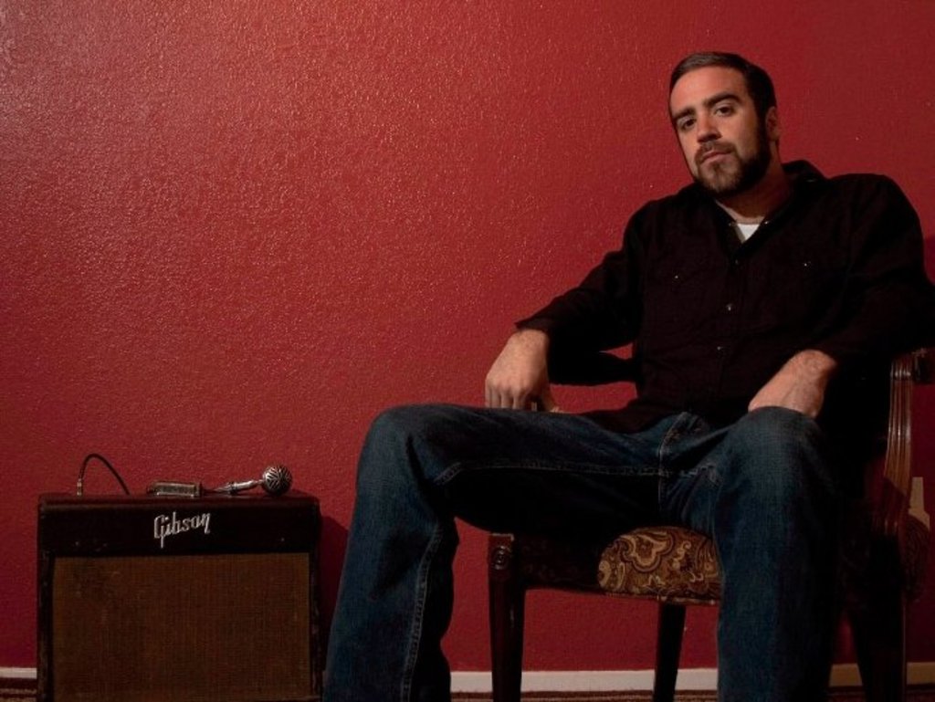 Auf dem Bild ist Greg Izor in einem Sessel sitzend zu sehen.