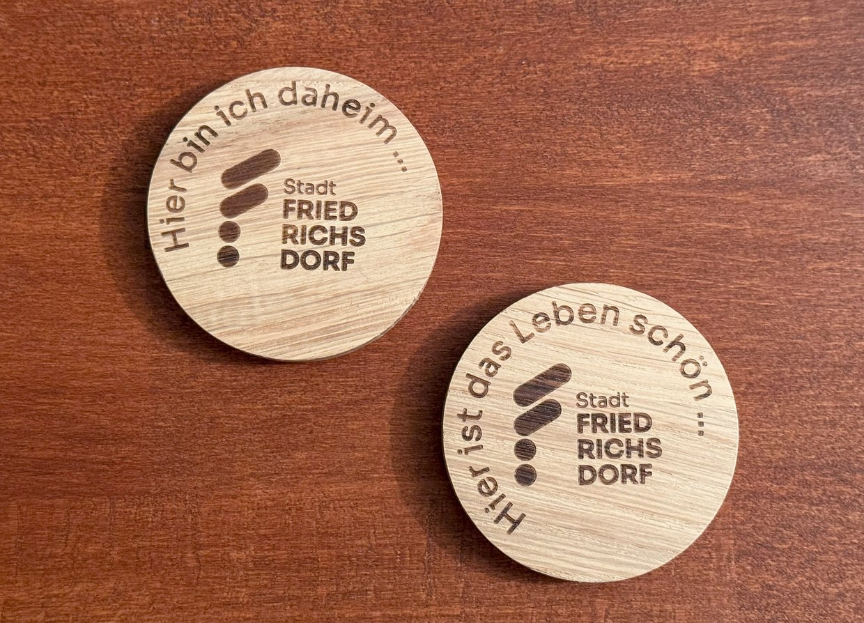Auf dem Bild sind zwei Holzmagnete mit Stadtlogo und Schriftzug zu sehen.