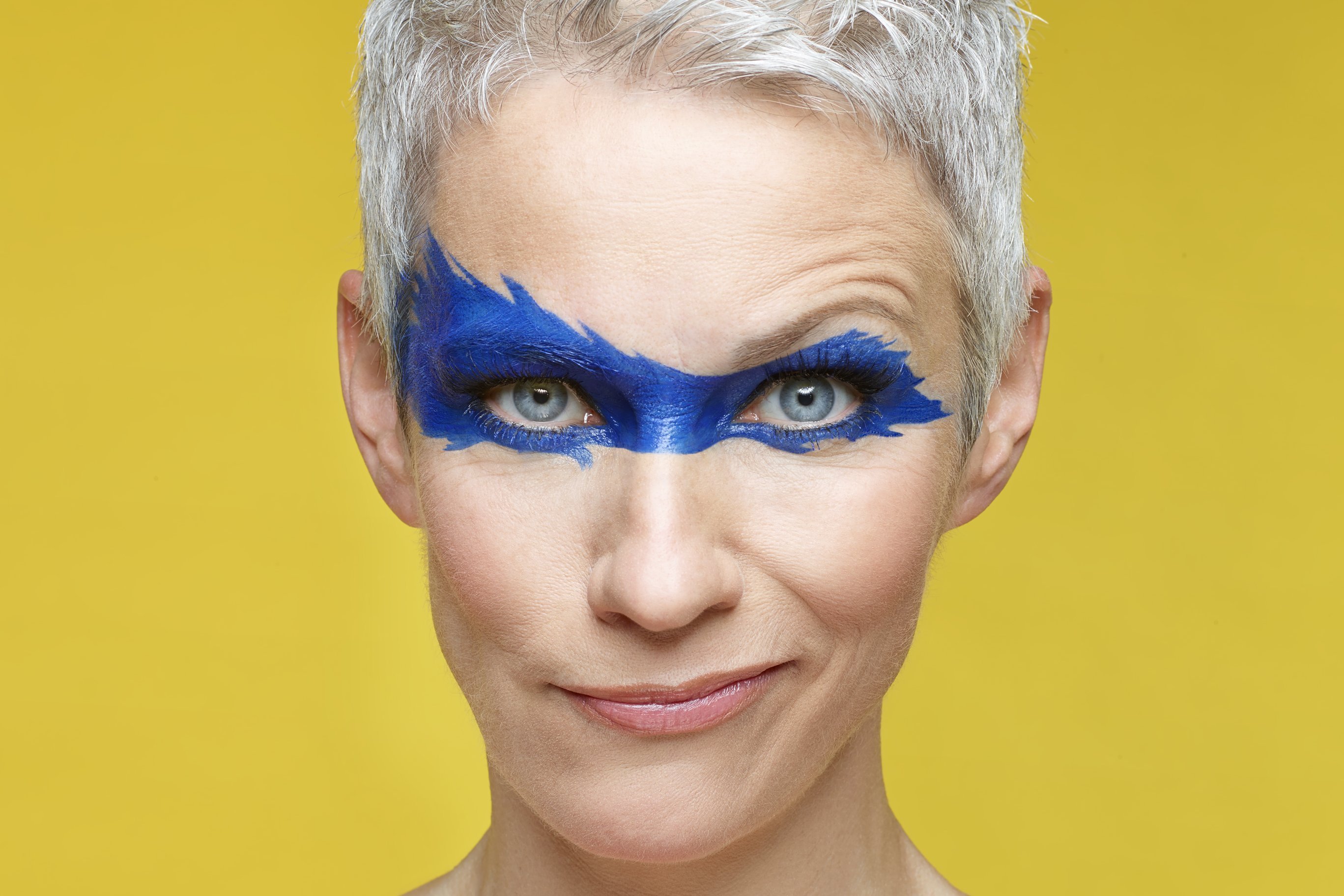 Auf dem Bild ist Kabarettistin Tina Häussermann mit aufgemalter Superman-Maske zu sehen.