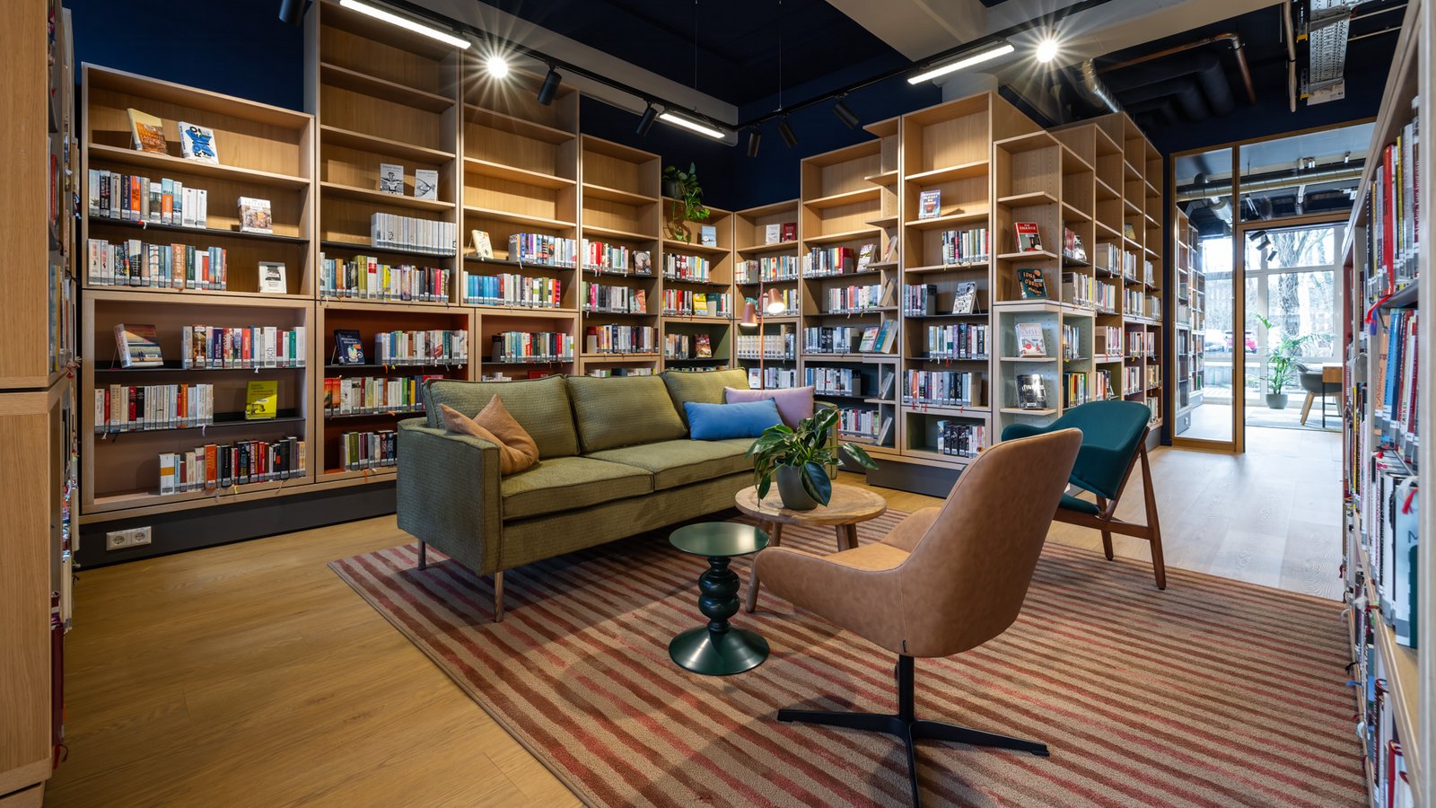 Inmitten von Bücherregalen stehen ein gemütliches Sofa und zwei Sessel um einen kleinen Tisch herum.