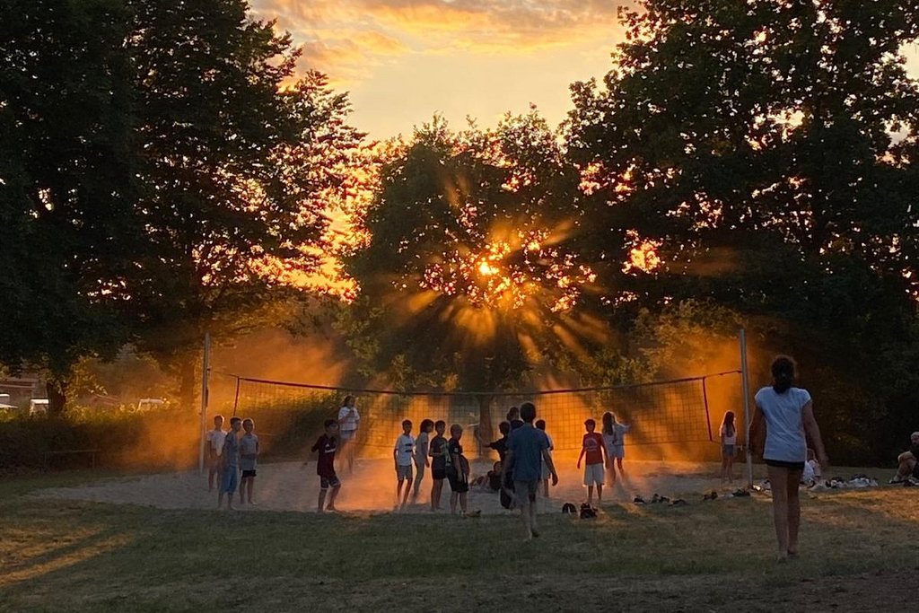 Kinder rennen beim Sonnenuntergang zum Volleyballfeld auf dem Gelände der Jugendherberge in Pottenstein