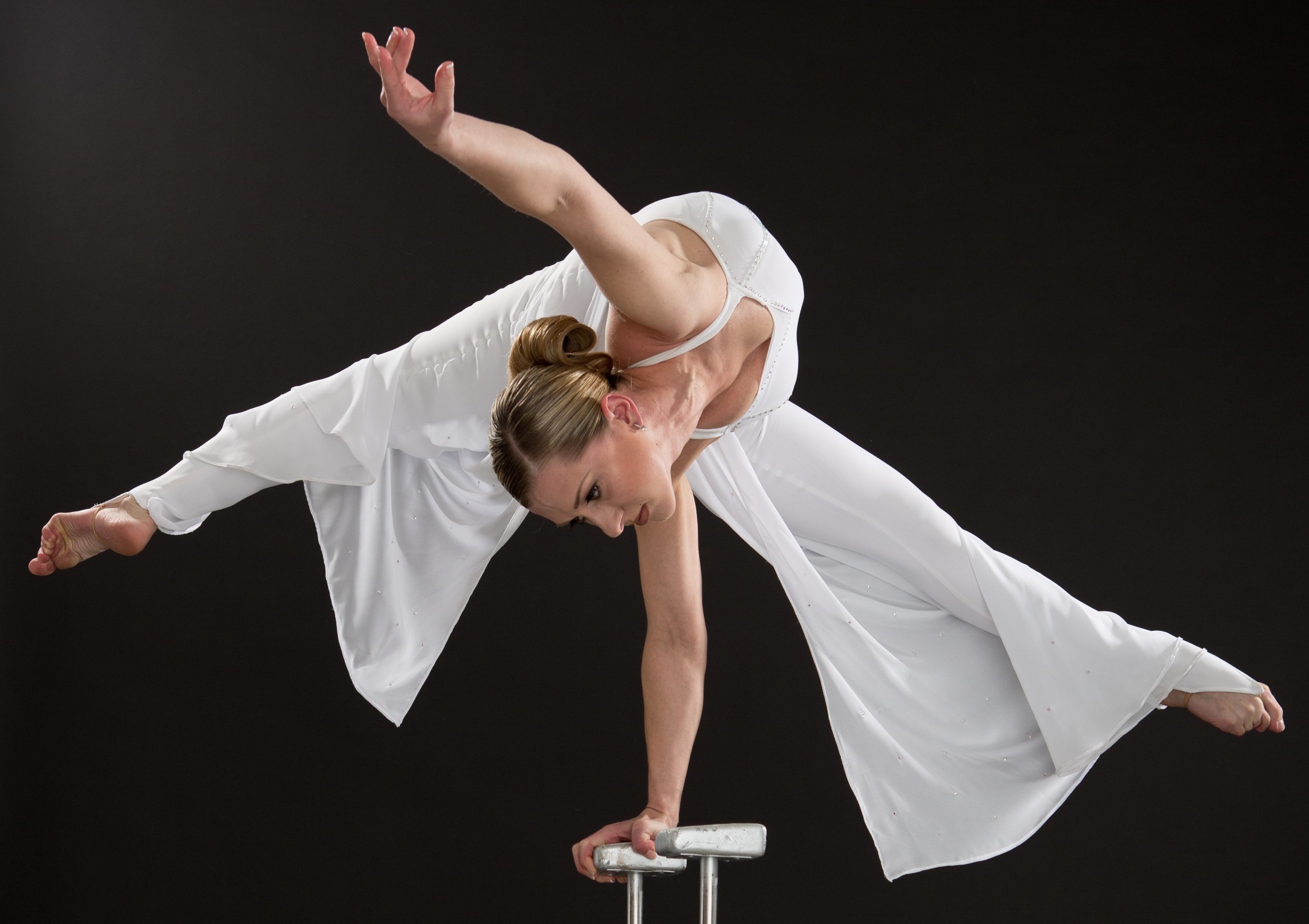 Auf dem Bild ist eine Akrobatin zu sehen, die einen einarmigen Handstand macht.