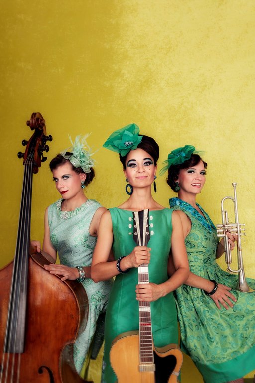 Auf dem Bild sind die drei Musikerinnen von Zucchini Sistaz in grünen Kleidern zu sehen.