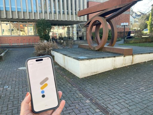 Das Bild zeigt ein Smartphone auf dem das Logo der Stadt Friedrichsdorf, ein großes farbiges "F", zu sehen ist.