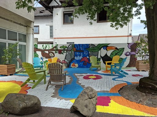 Bunt gestaltete Stadtterasse mit Sesseln, Bäumchen und fabenfrohen Wänden zum Verweilen für alle.