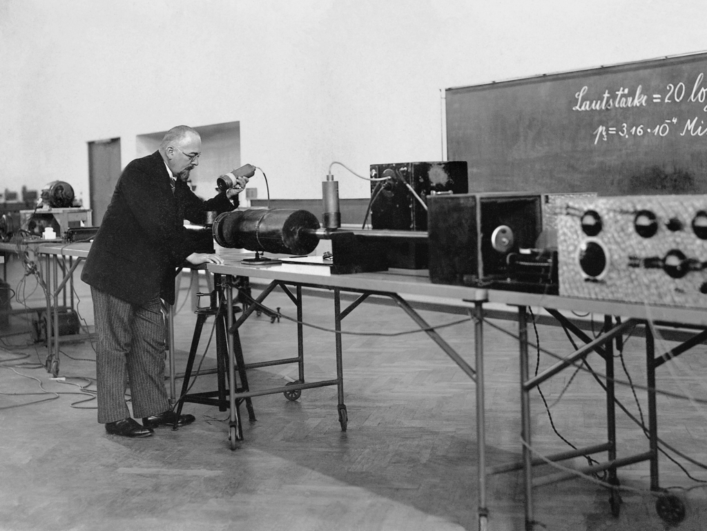 Das Bild zeigt Professor Karl Willy Wagner in einem wissenschaftlichen Kontext, bei der Arbeit und Präsentation zur Vokalsynthese.