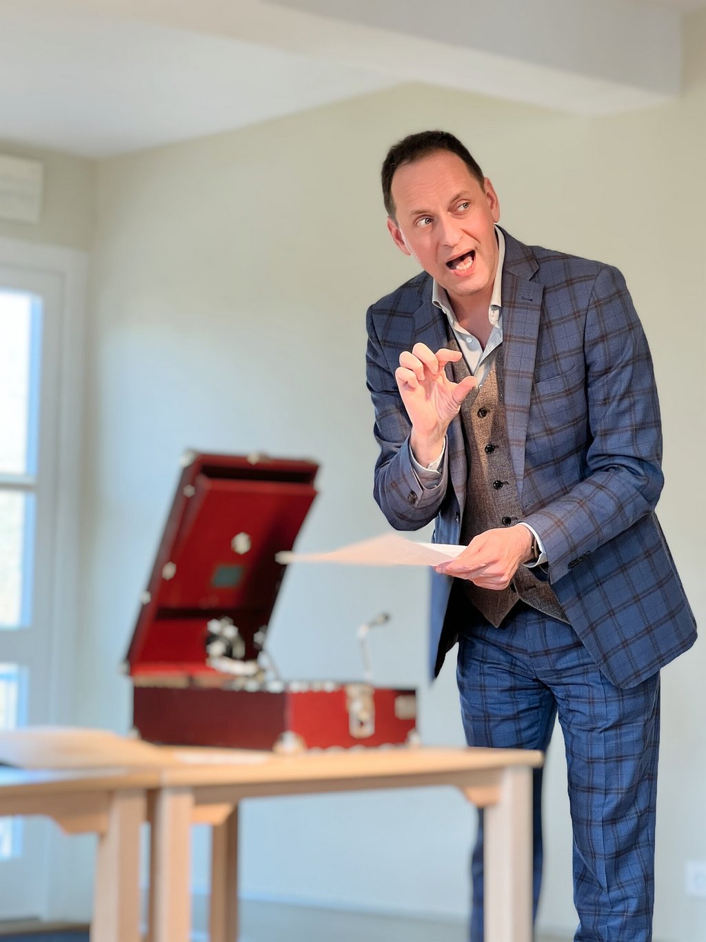 Auf dem Bild ist Jo van Nelsen zu sehen. Er steht vor einem offenen Koffer und spricht.