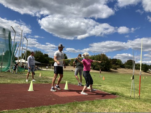 Eine interessierte Sportlerin lässt sich den Speerwurf erklären.