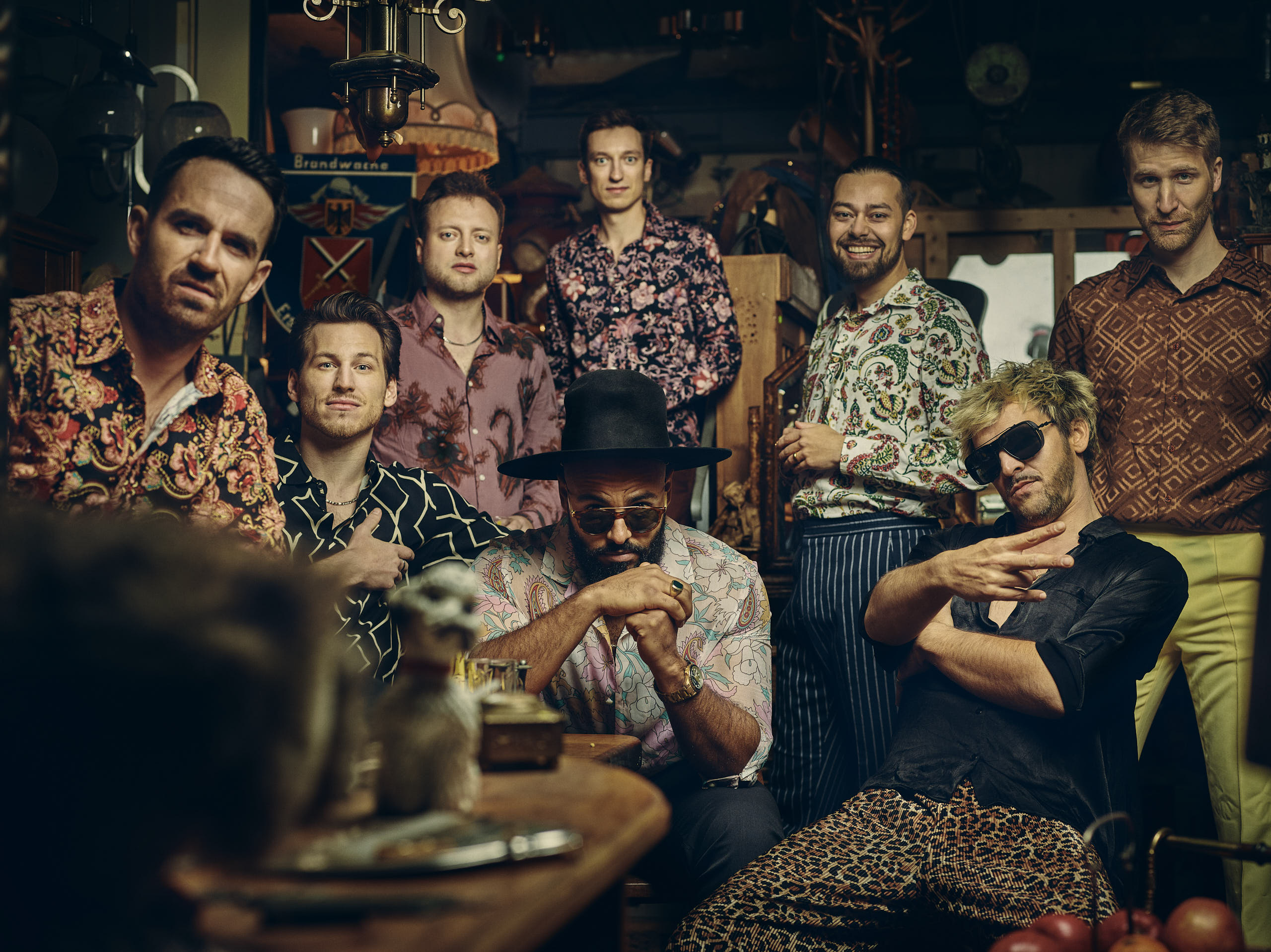 Auf dem Bild ist die siebenköpfige Band sitzend und stehend in Vintageklamotten zu sehen.