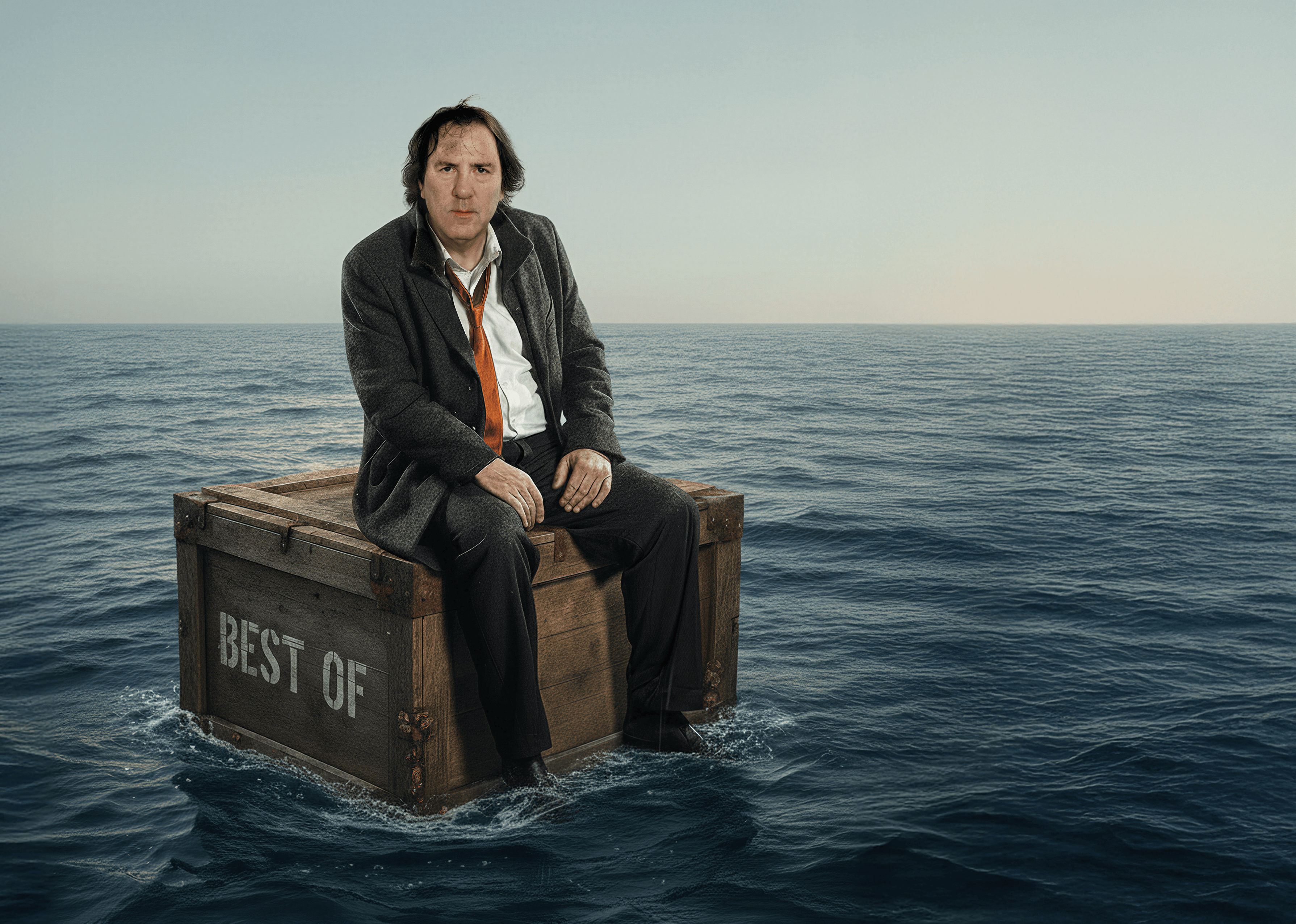 Auf dem Bild ist der Kabarettist Stefan Waghubinger auf einem Koffer sitzend im Meer treibend zu sehen.